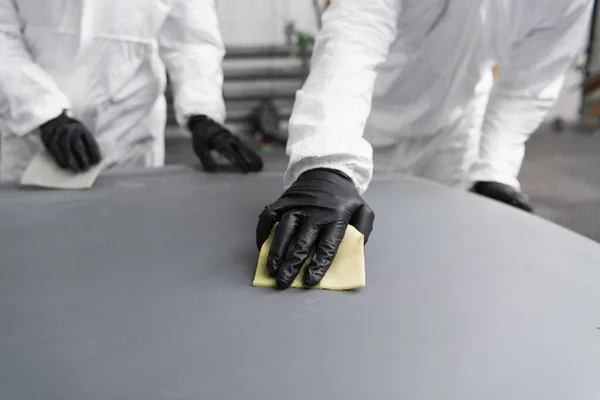 Vista ritagliata del lavoratore in tuta protettiva che lavora con carta vetrata e cappuccio auto in garage — Foto stock