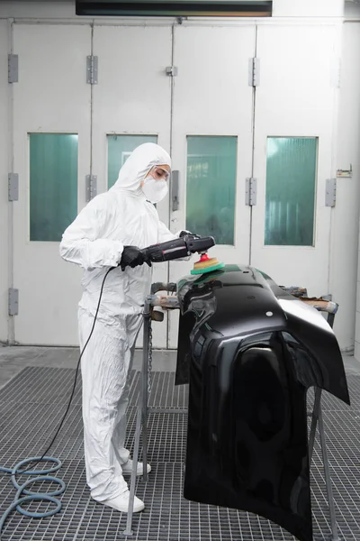 Workwoman en costume de protection polissage pièce de voiture dans le garage — Photo de stock