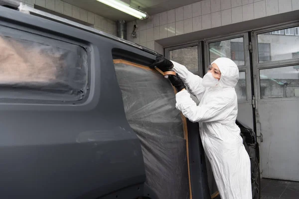 Arbeiterin in Schutzanzug klebt Klebeband auf Auto im Einsatz — Stockfoto