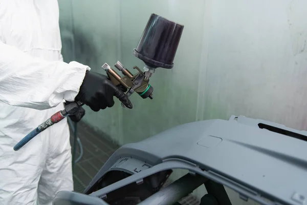 Vista recortada del trabajador en traje de materiales peligrosos y guante que sostiene el aerógrafo cerca de la pieza del coche en servicio - foto de stock