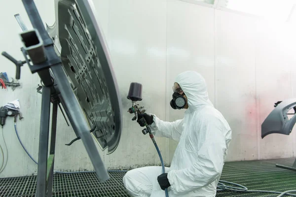 Side view of workman in respirator coloring car part in garage — Stockfoto