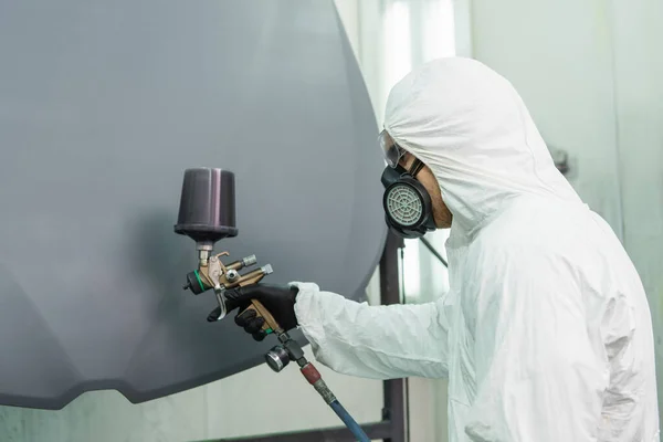 Side view of workman in respirator coloring car hood while working in service — стоковое фото