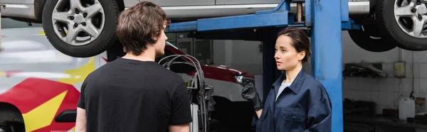 Réparatrice parlant à un collègue près des voitures dans le garage, bannière — Photo de stock