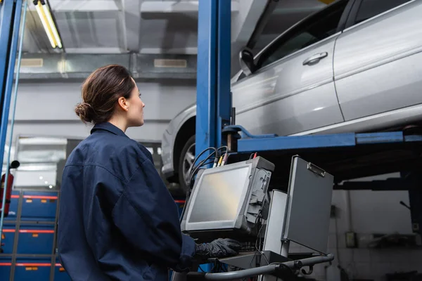 Side view of workwoman using computer near car in service — Fotografia de Stock