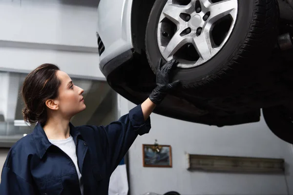 Side view of mechanic looking at car wheel in service — Stock Photo