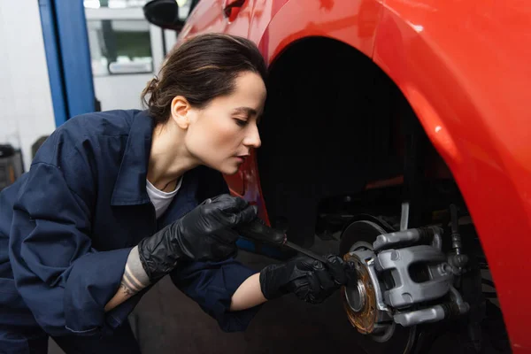 Side view of mechanic using screwdriver on car wheel in service — Fotografia de Stock