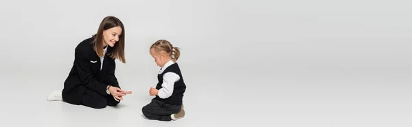 Cheerful mother showing fingers to child with down syndrome on grey, banner — Foto stock