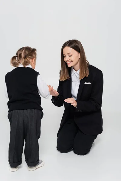 Cheerful mother holding hands with disabled daughter isolated on grey - foto de stock