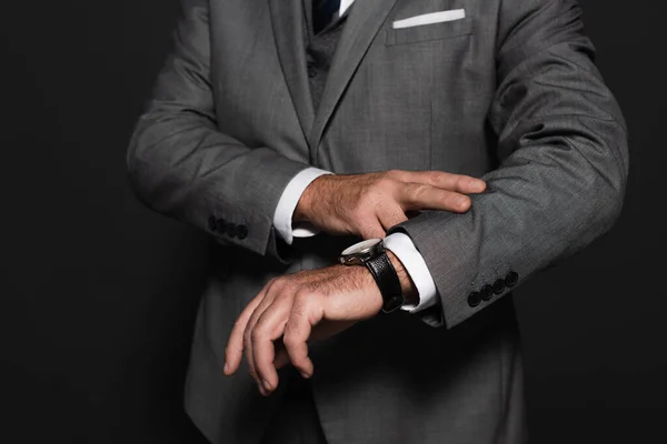 Partial view of man in formal wear checking time on wristwatch isolated on dark grey — Stock Photo