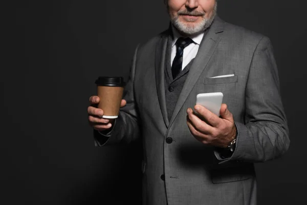 Cropped view of senior bearded businessman with mobile phone and paper cup on dark grey — Photo de stock