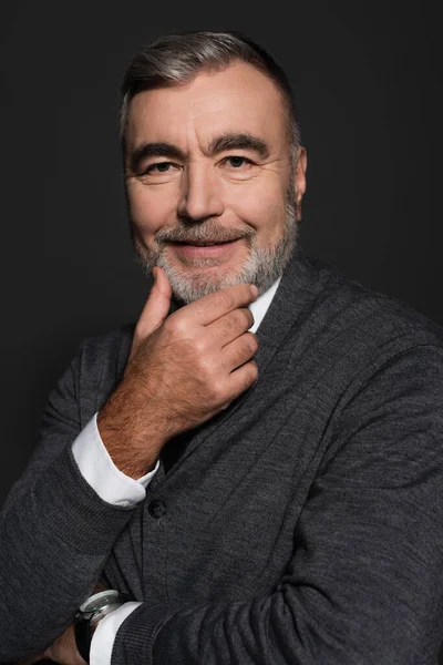 Happy senior businessman touching chin while smiling at camera isolated on grey — Stockfoto