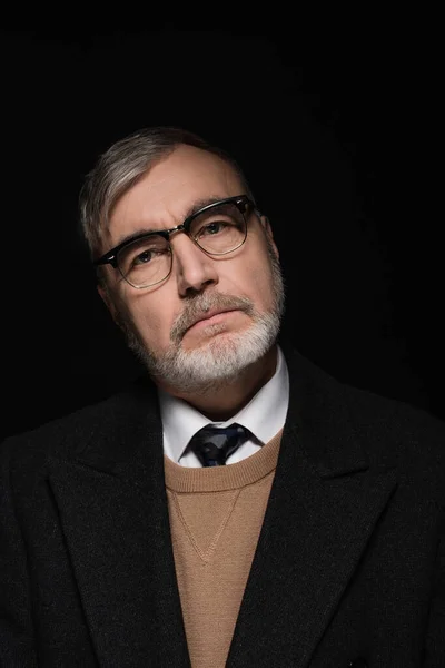 Bearded senior man in eyeglasses looking at camera isolated on black — Stock Photo