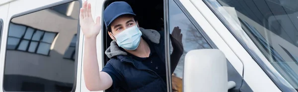 Delivery man in medical mask waving hand while driving auto, banner — Stock Photo