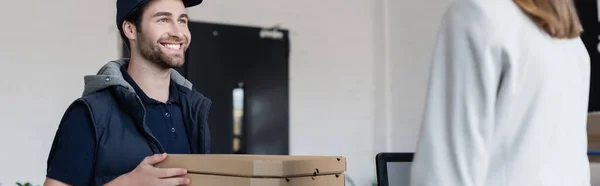 Happy delivery man holding pizza boxes near businesswoman in office, banner — Stock Photo