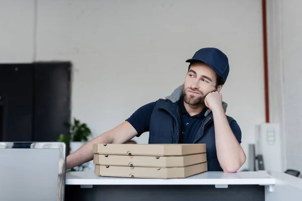 Upset courier standing near pizza boxes on reception in office - foto de stock