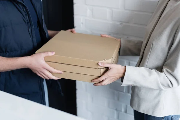 Обрізаний вид бізнес-леді і кур'єра, що тримає коробки для піци в офісі — стокове фото