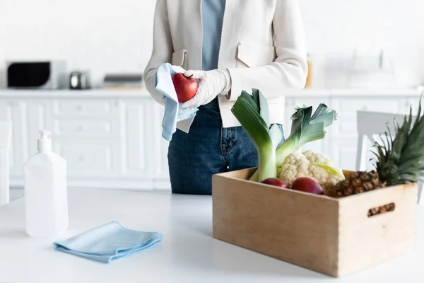 Cropped view of woman in latex gloves cleaning apple with rag at home — Photo de stock