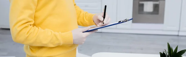 Cropped view of man in latex gloves writing on clipboard near pineapple in kitchen, banner — Stockfoto