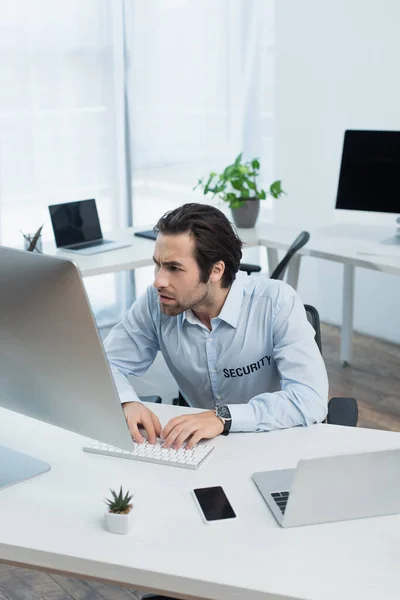 Напружений чоловік, який дивиться на монітор комп'ютера під час роботи в кімнаті спостереження — стокове фото