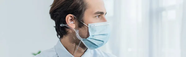 Security man in medical mask and earphones looking away in office, banner — Stock Photo