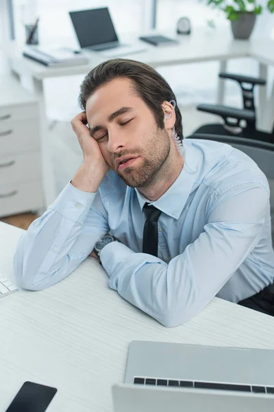 Gelangweilter Security-Mann mit Kopfhörer schläft am Arbeitsplatz im Büro — Stockfoto