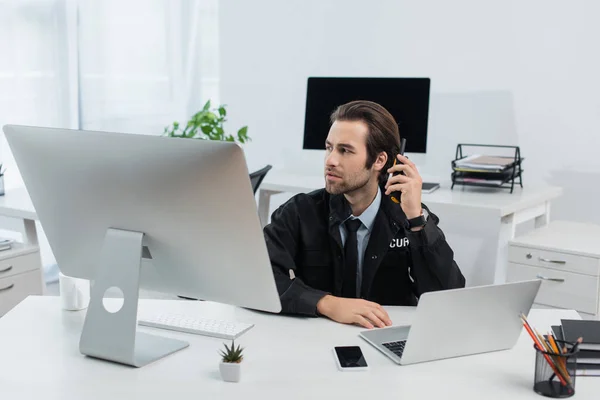 Uomo della sicurezza chiama walkie-talkie vicino ai computer nella sala di sorveglianza — Foto stock