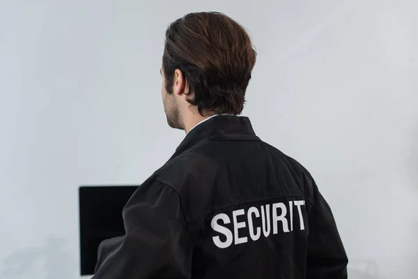 Vista posteriore della guardia in uniforme nera con iscrizione di sicurezza in ufficio — Foto stock