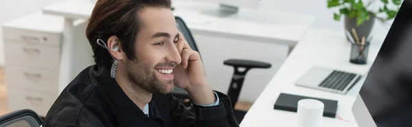 Cheerful security man in earphone looking at blurred computer monitor, banner — Stock Photo