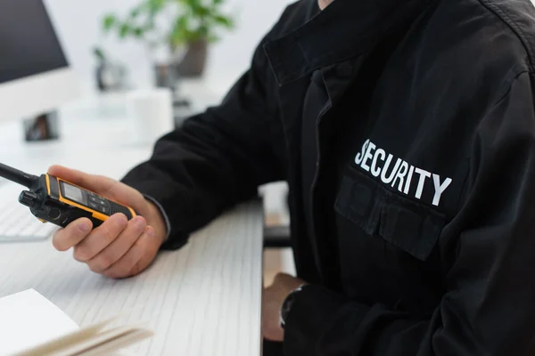 Vista ritagliata dell'uomo di sicurezza in uniforme nera con walkie-talkie in ufficio — Foto stock