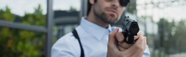 Vista parcial del hombre de seguridad borroso con pistola al aire libre, pancarta — Stock Photo