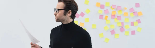 Unzufriedener Mann blickt auf Dokument neben klebrigen Zetteln an grauer Wand, Banner — Stockfoto