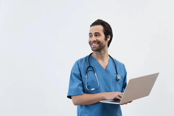 Médico sonriente con portátil mirando hacia otro lado aislado en gris - foto de stock