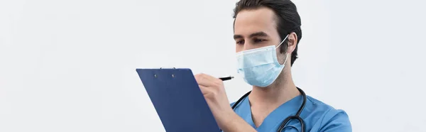 Врач в медицинской маске написания диагноза на планшете изолированы на серый, баннер — стоковое фото