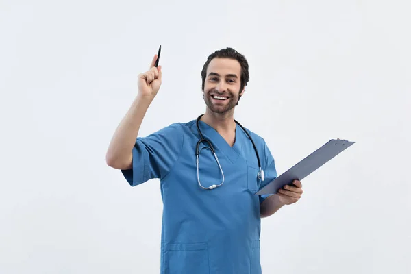 Щасливий лікар з кишені вказує вгору з ручкою ізольовано на сірому — стокове фото