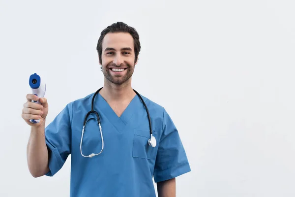 Fröhlicher Arzt mit Stethoskop und Pyrometer, der auf grau isoliert in die Kamera blickt — Stockfoto