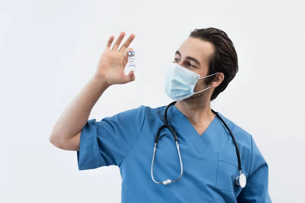 Young doctor in medical mask holding coronavirus vaccine isolated on grey — Stock Photo