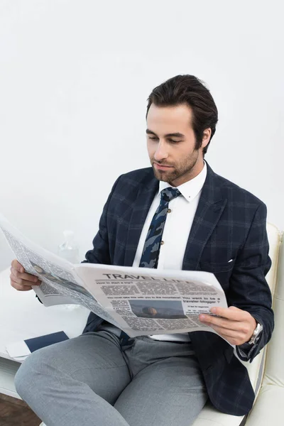 Junger Mann liest Zeitung, während er in der Abflughalle wartet — Stockfoto