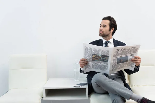 Homme avec la vie de voyage journal regardant loin tout en étant assis dans le salon de départ — Photo de stock