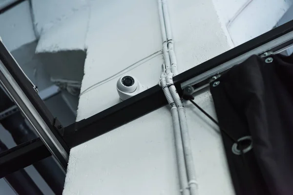 Vista de ángulo bajo de la cámara de monitoreo en la construcción de metal cerca de la pared blanca - foto de stock