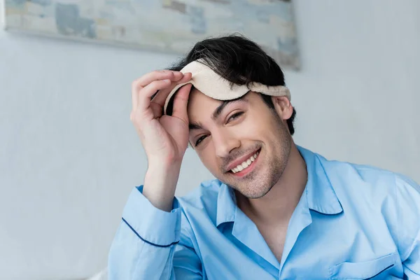 Fröhlicher junger Mann legt Schlafmaske ab und blickt in Kamera — Stockfoto