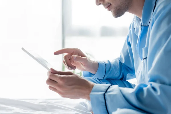 Vista parziale dell'uomo in pigiama blu con tablet digitale in camera da letto — Foto stock