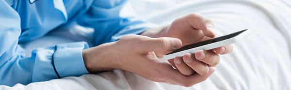Обрезанный вид человека сообщения на мобильном телефоне в спальне, баннер — стоковое фото