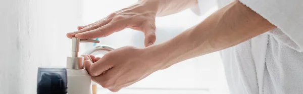 Partial view man pushing on dispenser while applying liquid soap on hands, banner — Stock Photo