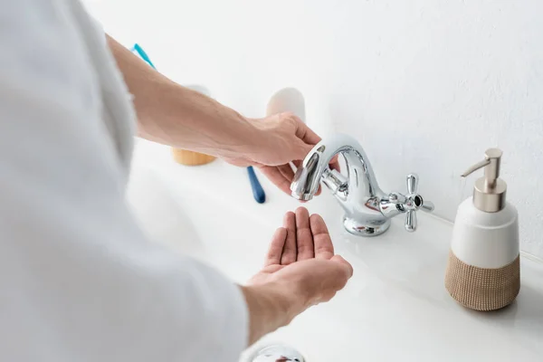 Vista parcial del grifo de apertura de hombre borroso en el baño - foto de stock