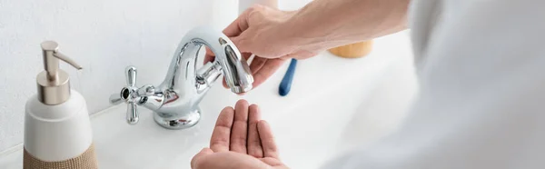 Vista ritagliata del rubinetto di apertura dell'uomo in bagno, banner — Foto stock