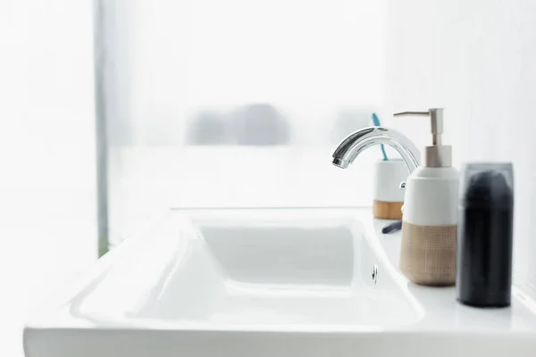 Shaving foam and dispenser with liquid soap on white sink in bathroom — Stock Photo