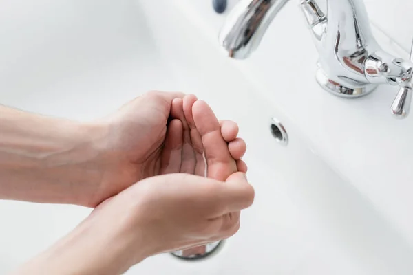 Обрізаний вид людини, що миє руки у ванній — стокове фото