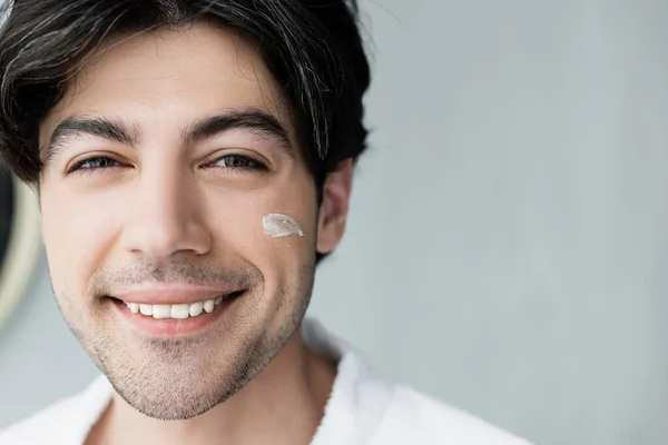 Vista de perto do homem sorridente com creme cosmético no rosto — Fotografia de Stock