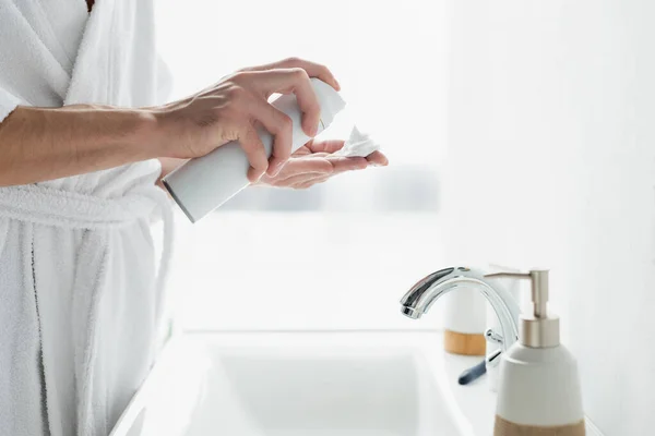 Abgeschnittene Ansicht eines Mannes, der Rasierschaum auf der Hand in der Nähe des Waschbeckens im Badezimmer aufträgt — Stockfoto