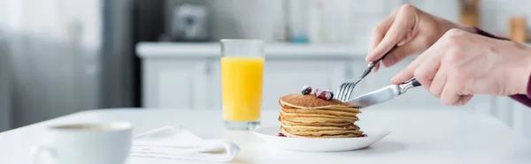 Partial view of man cutting pancakes near orange juice and coffee cup, banner — Stock Photo